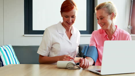 nurse checking blood pressure of senior patient