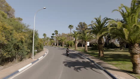 wide aerial of a couple riding on motorbike in marbella in summertime