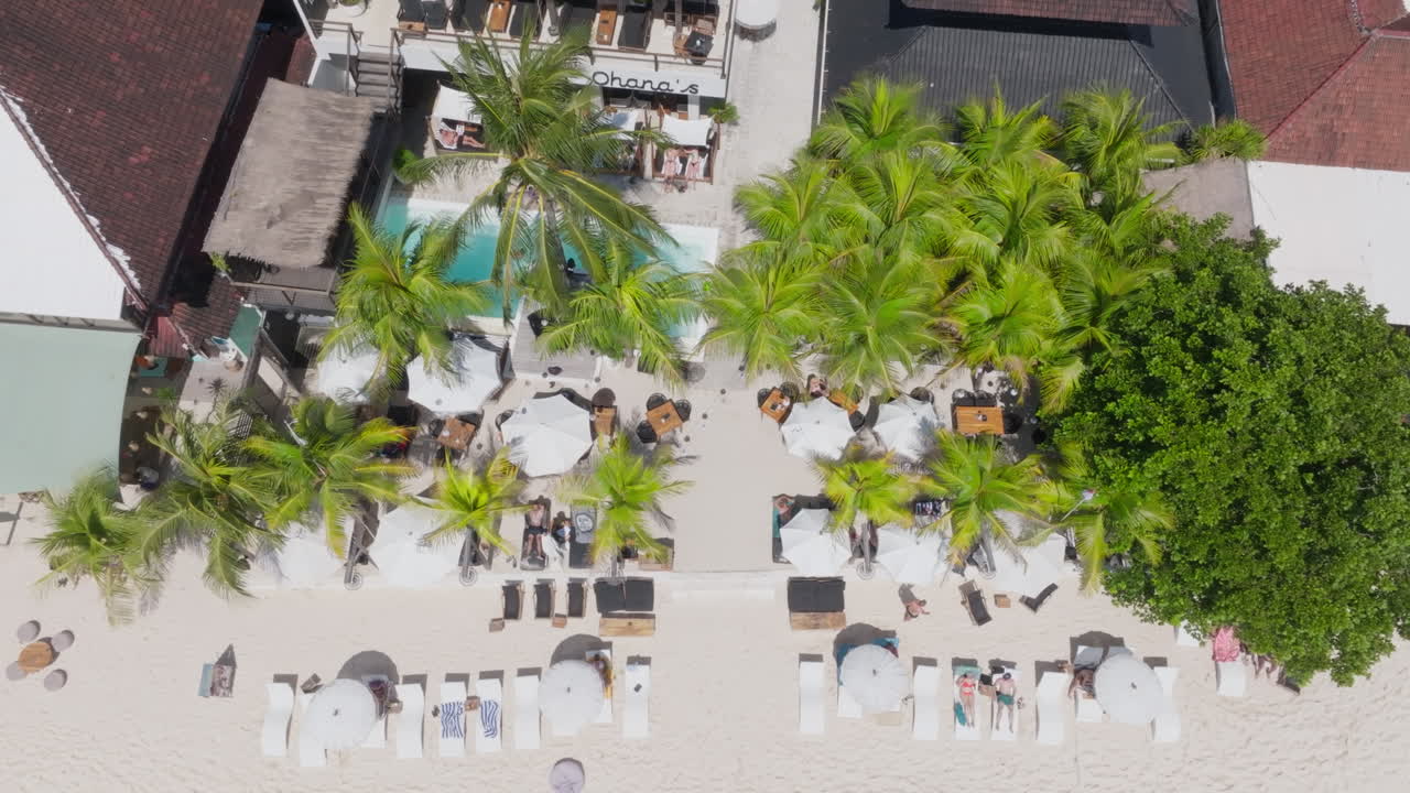 Overhead drone clip showing sun loungers and poolside area at luxury holiday resort