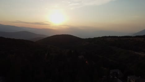 sun setting down behind silhouette of mountains landscape, aerial view