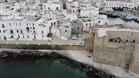 drone flies from sea over the monopoli castle and old town centre during dawn