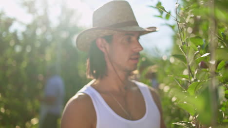 man tending to plants in a sunny orchard