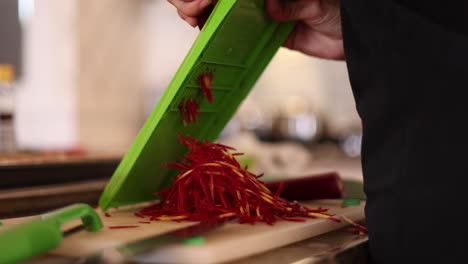 manos usando una cortadora de julienne para cortar zanahorias en tiras delgadas