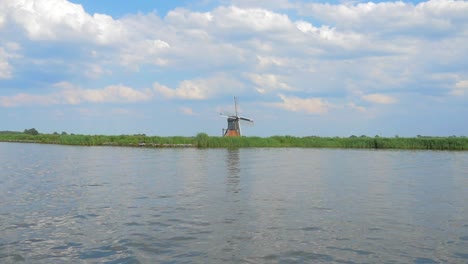 Holländische-Alte-Windmühle-Auf-Einem-Deich-In-Der-Nähe-Des-Wassers,-Ein-Kleiner-Dolly,-Der-In-Zeitlupe-Gedreht-Wurde