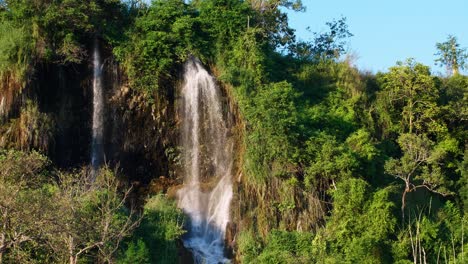 A-wide-view-of-the-natural-waterfall-that-flows-down-the-mountain-is-lit-by-the-evening-sun-in-Thailand