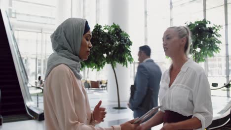 Businesswomen-interacting-with-each-other-in-the-lobby-at-office-4k