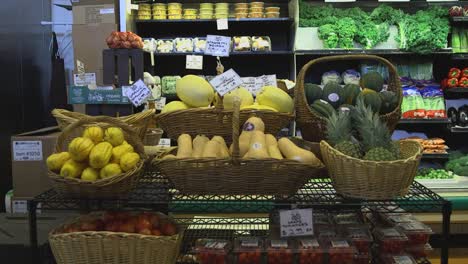 personas que pasan frente a la sección de frutas y verduras de un