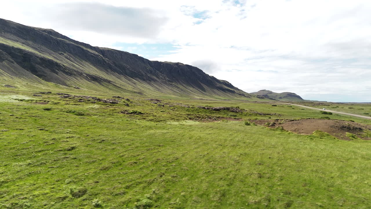 Vista aerea da drone di una strada sterrata che traccia le montagne lungo il fiordo Hvammsfjörður a Vesturland, in Islanda, che mostra altipiani remoti, valli verdi e drammatici pendii vulcanici