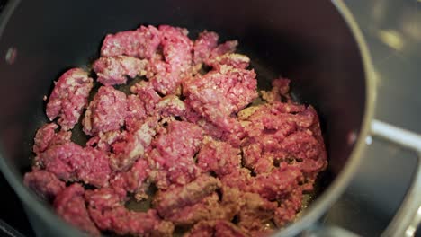 ground beef mince cooking in black pot with occasional stirring and lid lifting