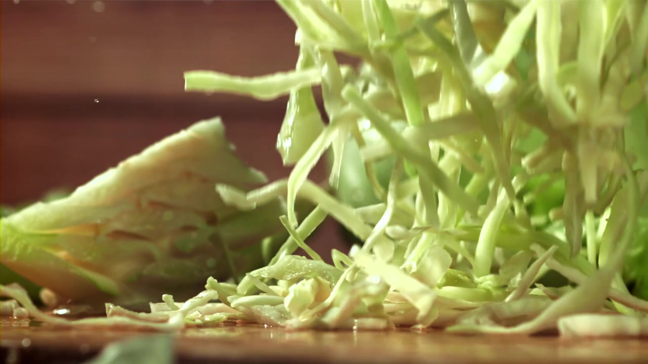 Shredded Cabbage Falling onto a Wet Wooden Surface in Slow Motion