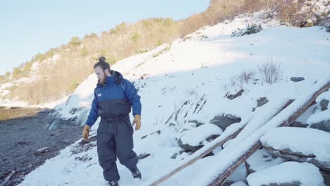 Mann-Wirft-Steine-Auf-Den-Schneebedeckten-Hügel