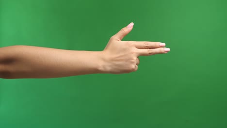 woman's hand making shooting gun, gesture. hand pistol gesture on isolated on green screen background. woman hand pointing with two fingers