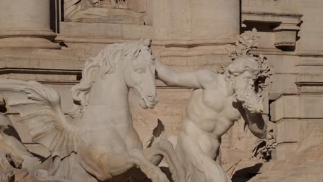 close-up of a triton taming a winged sea horse at the trevi fountain in rome, italy, showcasing mythological themes and marble detail in strong daylight.