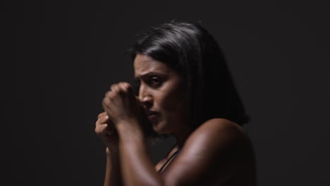 Profile-Studio-Shot-Of-Mature-Woman-Wearing-Gym-Fitness-Clothing-Exercising-Sparring