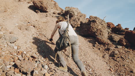 mujer subiendo escaleos empinados en el desierto post-apocalíptico