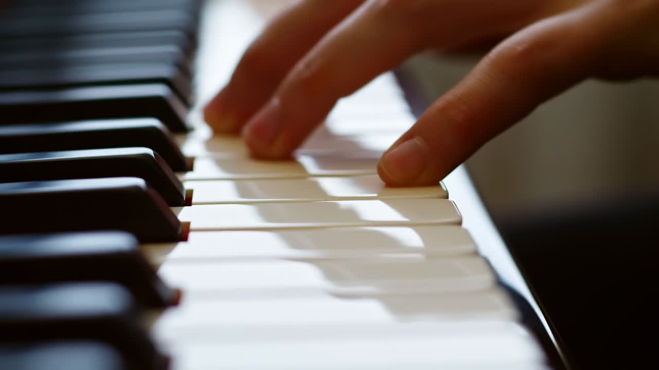 Primo piano di tasti di pianoforte, dita che suonano una melodia delicata in uno studio domestico illuminato dal sole, studente pianista che pratica la tecnica.