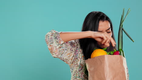 mujer con una bolsa de papel ecológico en las manos mirando pimienta,