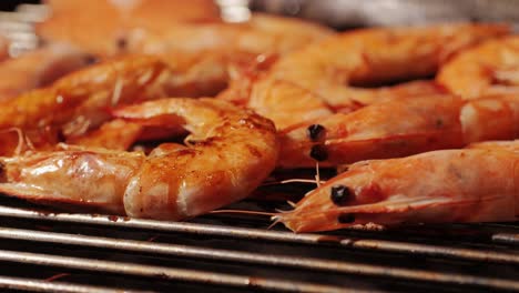 chef cooking shrimps with oil and spices on grill close-up. prawns on fire throwing them on pan. restaurant food concept. sea food barbecue.