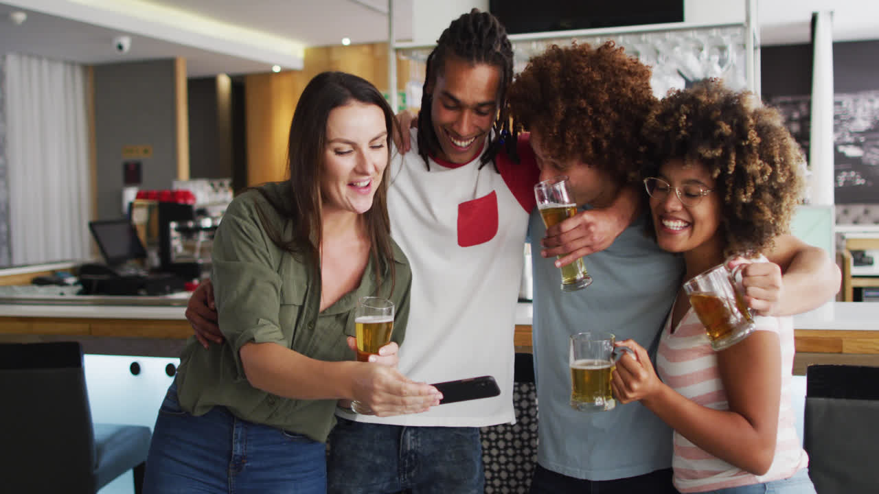 un grupo diverso de amigos felices bebiendo cervezas y tomando una selfie en un bar