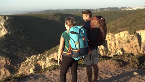pareja de excursionistas con mochilas de campamento de pie en el acantilado