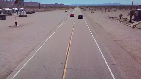 drone aerial over a lonely desert highway in arizona with route 66 painted on the pavement and car passing underneath 2