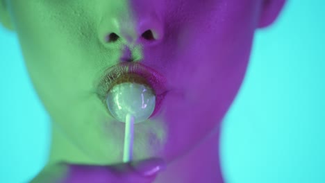 woman licking a lollipop - close up portrait with neon lighting