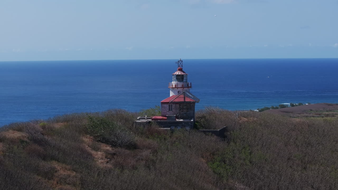 Aerial parallax of lighthouse on hill at Île Plate of Mauritius and open ocean