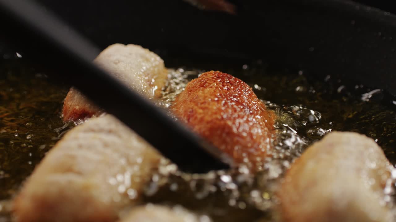 Portuguese croquettes broiling on black frying pan close-up macro. Breaded croquette of fish, potatoes and ham. Man cooking spanish food. High quality 4k footage