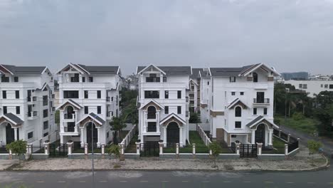 Una-Hilera-Recién-Construida-De-Grandes-Casas-Blancas-Idénticas-De-Estilo-Villa-De-Varios-Pisos-A-Lo-Largo-De-Una-Carretera-Suburbana