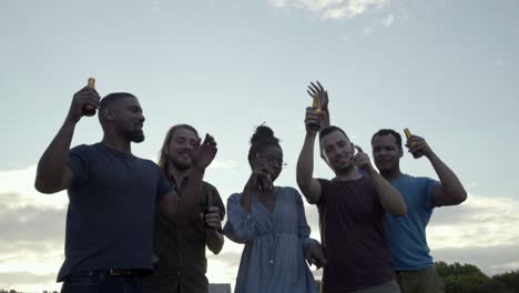 Relaxed-young-people-holding-bottles-and-dancing