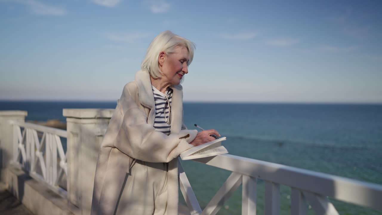 Senior Woman Writing in Notebook by the Sea