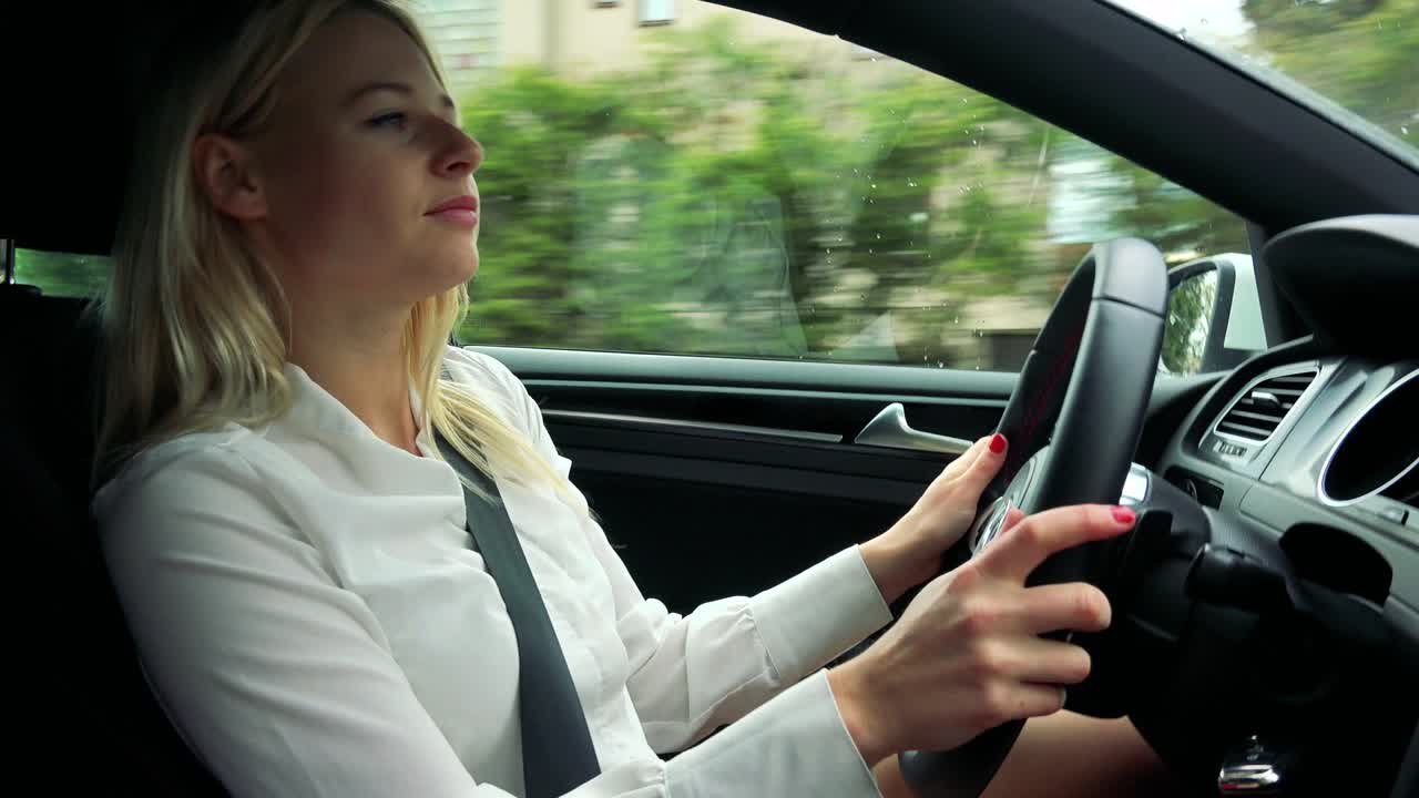 una joven rubia atractiva conduce un coche, escucha música y baila