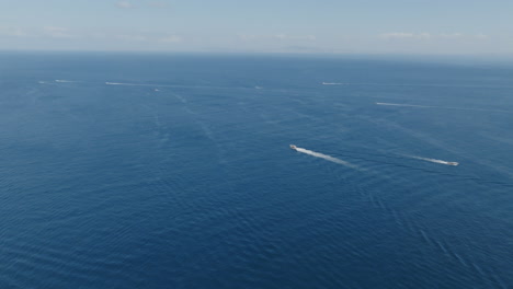 Wide-aerial-of-the-deep-blue-of-the-Mediterranean-with-boats-making-white-wakes-across-the-sea