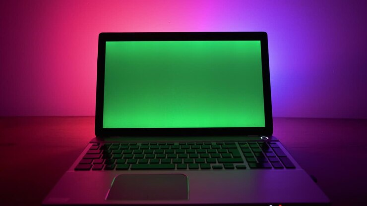 Green screen laptop with neon lights in the back. Green screen leptop standing on table.
