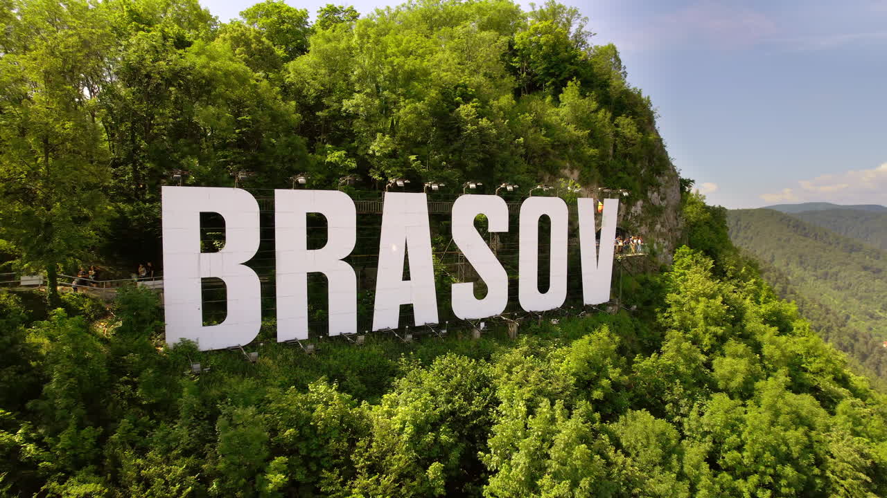 Cartel de Brasov en lo alto de la colina cerca de la ciudad, árboles verdes, turistas, Rumanía