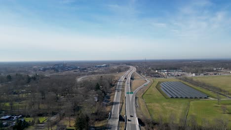 drohnenaufnahme des winters in ohio mit sonnenkollektoren neben einer autobahn, die durch eine kleine stadt führt