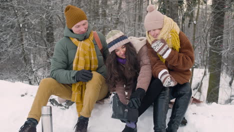 father, mother and daughter sitting in the snowy forest