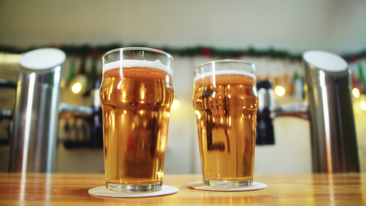 Due bicchieri di birra dorata su un bancone da bar in legno