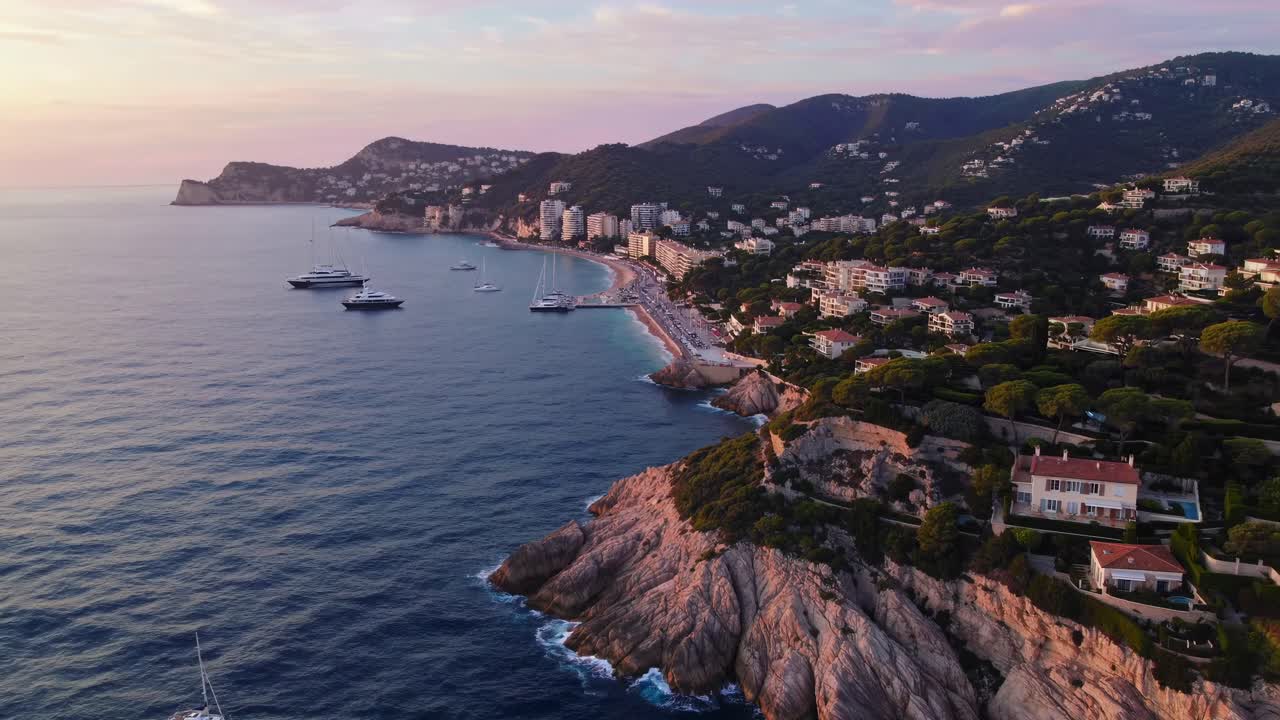 Un video aereo cattura uno splendido paesaggio costiero al tramonto, mettendo in mostra scogliere rocciose e lusso