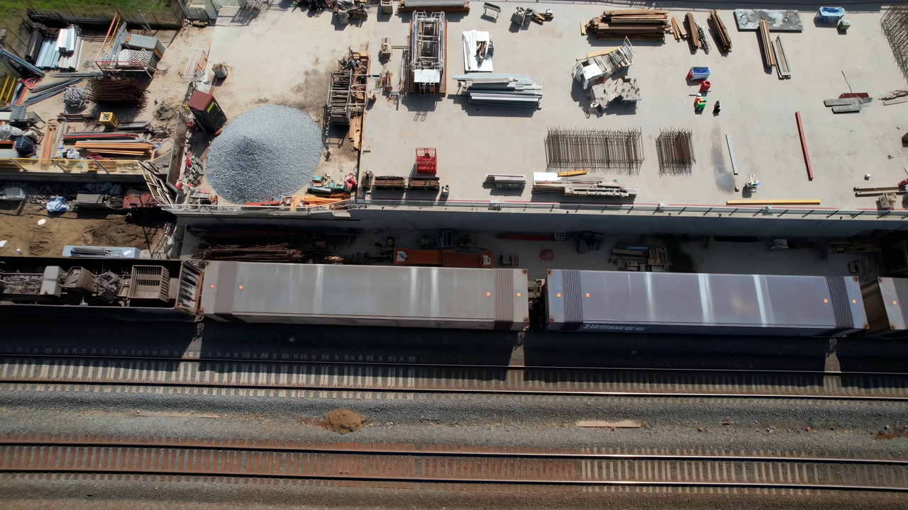 Aerial Railway Construction Site Showing Freight Cars, Gravel Pile, Stacked Materials, Machinery And Parallel