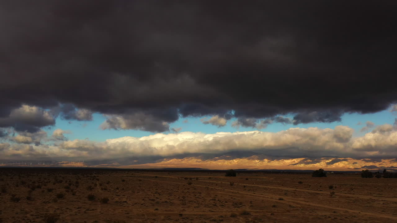 Menacing dark clouds fill the sky just before a violent cloudburst in the Mojave Desert - sliding aerial view