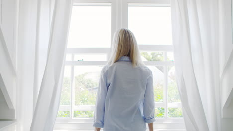 vista trasera de una pareja abriendo cortinas y mirando por la ventana