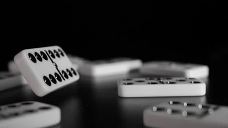 los dados de dominó blancos caen sobre un fondo negro