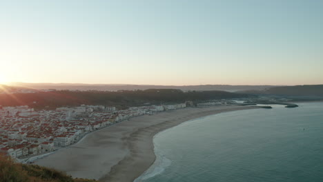 Paisaje-Urbano-Medieval-Junto-Al-Océano-Sereno-Durante-El-Amanecer-En-La-Playa-Norte-De-Nazare,-Portugal