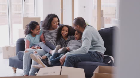 family taking a break and sitting on sofa celebrating moving into new home together