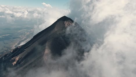 volcano peak surrounded by dense cloudscape in guatemala, aerial fpv view