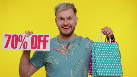 cheerful tourist man showing shopping bags and up to 70 percent off inscriptions banner black friday