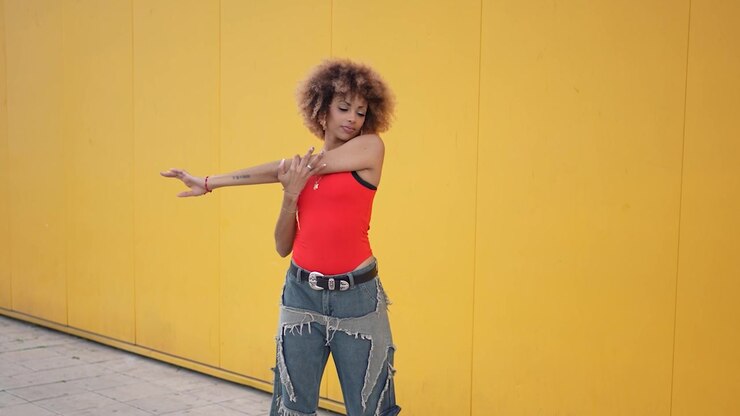 A fitness model is posing elegantly against a bright and vibrant yellow wall background