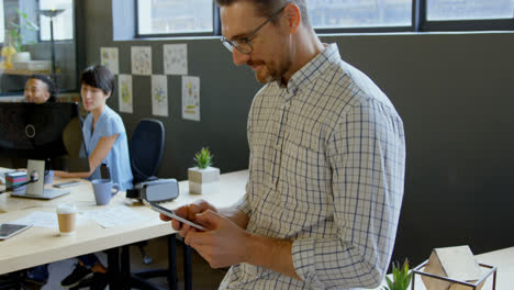 Smiling-male-executive-using-mobile-phone-at-desk-in-office-4k