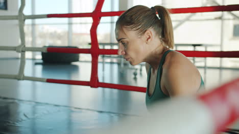 female boxer resting in boxing ring
